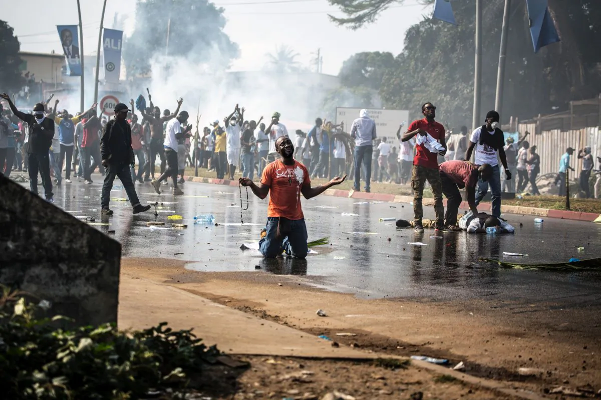A supporter of Gabonese opposition leader Jean Ping prays in front of security forces blocking a demonstration trying to reach the electoral commission in Libreville, Gabon, on Aug. 31, 2016, as another protestor lays on the ground in distress. Ali Bongo Ondimba won the election by a very narrow margin, a result hotly contested by the opposition. (Marco Longari/AFP/Getty Images)