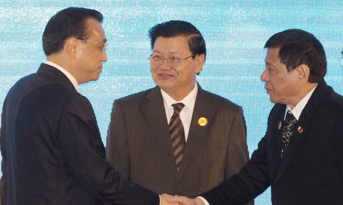 Chinese Premier Li Keqiang, left, shakes hands with Philippine's President Rodrigo Duterte, right, as Laos' Prime Minister Thongloun Sisoulith, watches during the 19th ASEAN-China summit, in Vientiane, Laos, Wednesday, Sept. 7, 2016. (AP Photo/Gemunu Amarasinghe)