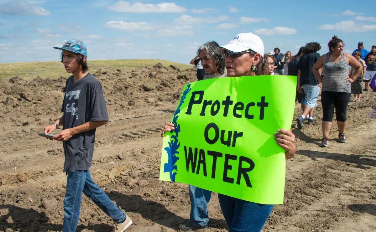A protester holds a sign reading "Protect Our Water" as Native Americans and their supporters walk on land designated for the Dakota Access Pipeline (DAPL), after protestors confronted contractors and private security guards working on the oil pipeline project, forcing them to retreat, near Cannon Ball, N.D., on Sept. 3, 2016. (Robyn Beck/AFP/Getty Images)