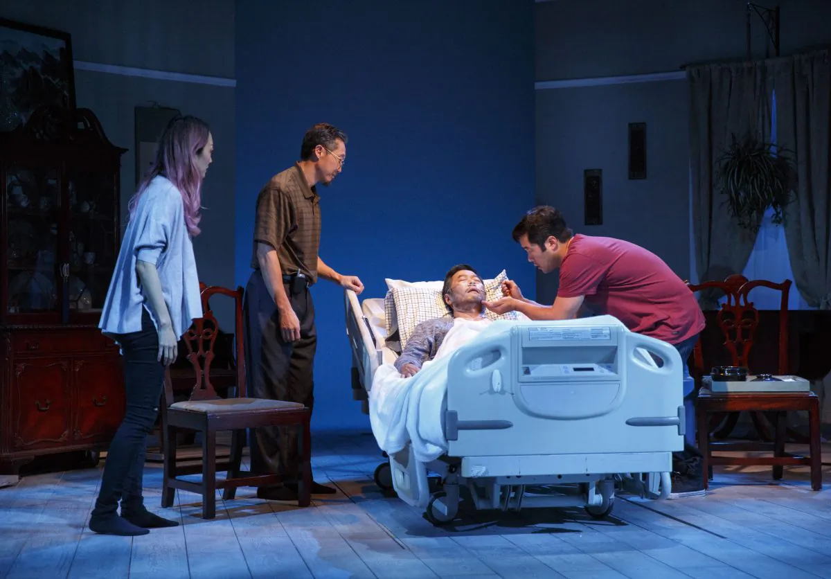 (L–R) Cornelia (Sue Jean Kim) Uncle (Joseph Steven Yang) gather around the dying father (Stephen Park) of Ray (Tim Kang), in “Aubergine.” (Joan Marcus)