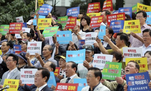 South Korean shout slogans during a rally denouncing North Korea's latest nuclear test in Seoul, South Korea, Monday, Sept. 12, 2016. North Korea is capable of detonating another nuclear device anytime at one of its unused tunnels at the country's main atomic test site, Seoul official said Monday, three days after the country carried out its fifth bomb explosion. The letters read "Overthrow Kim Jong Un and Discard North Korea's nuclear." (AP Photo/Lee Jin-man)