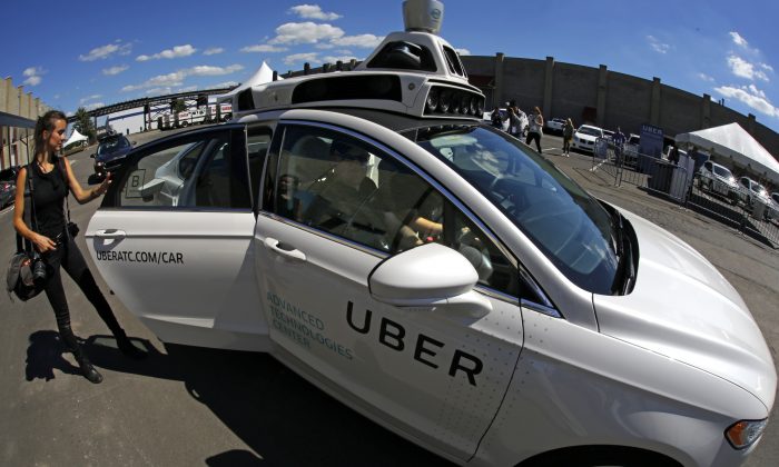 A journalist gets in a self driving Uber for a ride during a media preview at Uber's Advanced Technologies Center in Pittsburgh Monday, Sept. 12, 2016. Starting Wednesday morning, Sept. 14, 2016 dozens of self-driving Ford Fusions will pick up riders who opted into a test program with Uber. While the vehicles are loaded with features that allow them to navigate on their own, an Uber engineer will sit in the driver’s seat and seize control if things go awry. (AP Photo/Gene J. Puskar)