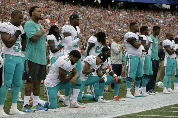 Miami Dolphins Arian Foster (29), Kenny Stills (10) and Michael Thomas (31) kneel during the national anthem before an NFL football game against the New England Patriots Sunday, Sept. 18, 2016, in Foxborough, Mass. (AP Photo/Steven Senne)