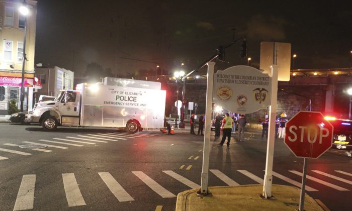 Bomb squad personnel stand around the scene of an explosion near the train station, early Monday, Sept 19, 2016, in Elizabeth, N.J. A suspicious device found Sunday night in a trash can near a New Jersey train station exploded early Monday as a bomb squad robot attempted to disarm it. (Jessica Remo/NJ Advance Media via AP)