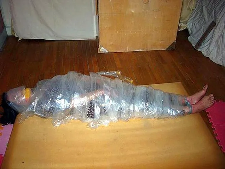 A re-enactment shows the torture method of being wrapped up in tape (Minghui.org)