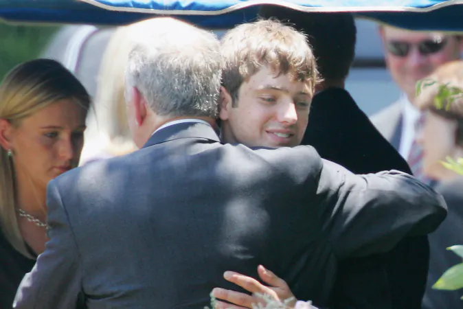 In this June 29, 2006, file photo, John Ramsey hugs his son, Burke, facing camera, at the graves of his wife, Patsy, and daughter JonBenet, during services for his wife at the St. James Episcopal Cemetery in Marietta, Ga. Burke Ramsey filed a $150 million lawsuit against Werner Spitz after he claimed Ramsey killed his sister, Jon Benet on Oct. 7. (AP Photo/Ric Feld, File)