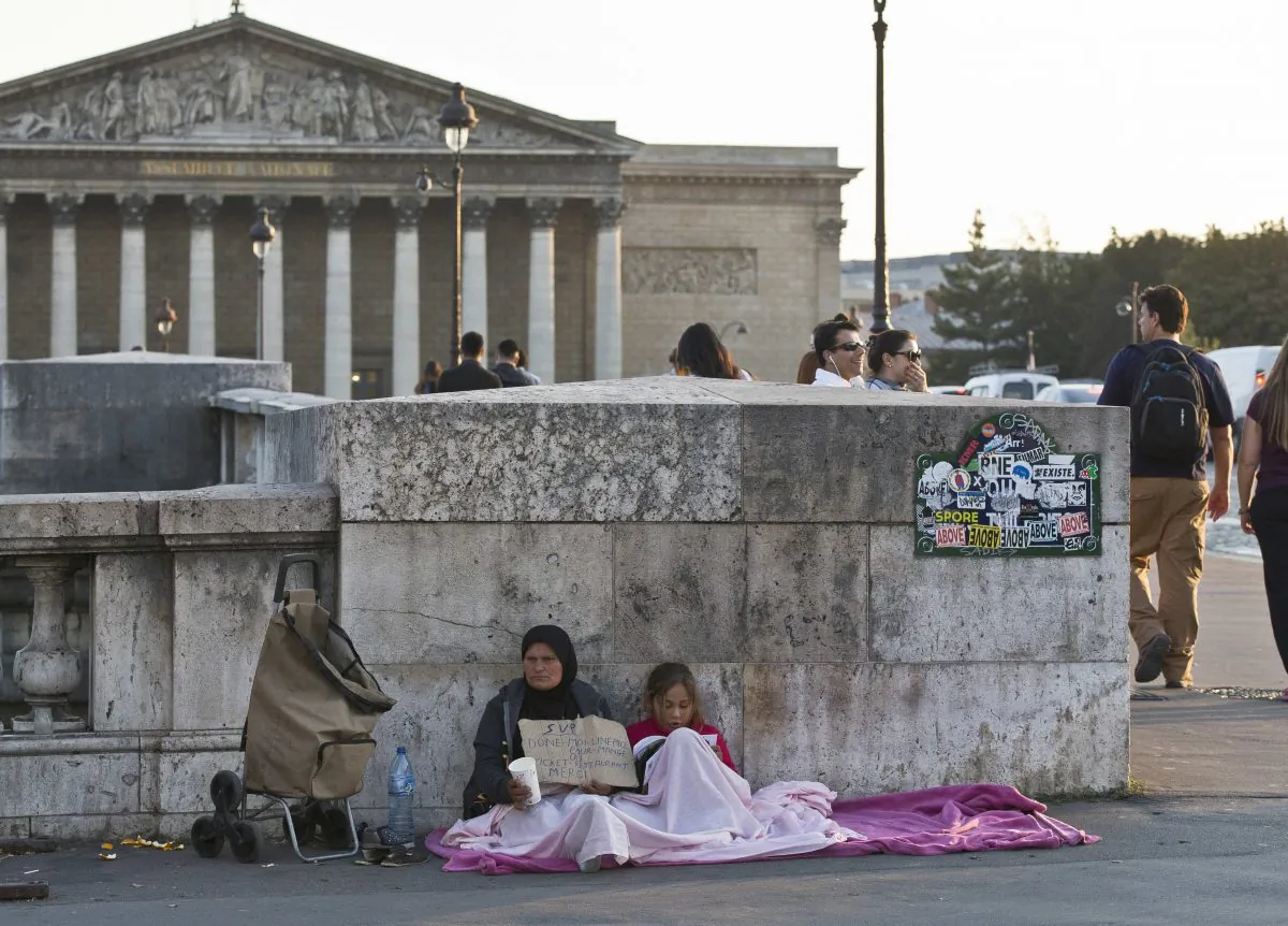 A migrant family beg for money at the Concorde bridge next to the French parliament in Paris on Sept.21, 2016. (AP Photo/Michel Euler)