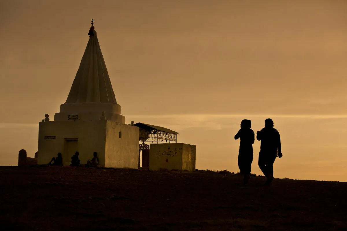 The sun sets as women visit a Yazidi shrine overlooking at Kankhe Camp for the internally displaced in Dahuk, northern Iraq, on May 18, 2016. (AP Photo/Maya Alleruzzo)