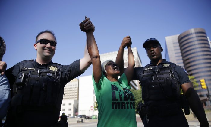 Angie Pitts, of Tulsa, holds hands with Tulsa Police officers while protesting the death of Terence Crutcher, who was shot by police, in front of the Tulsa Country Courthouse, in Tulsa, Okla., on Sept. 22, 2016. (Mike Simons/Tulsa World via AP)