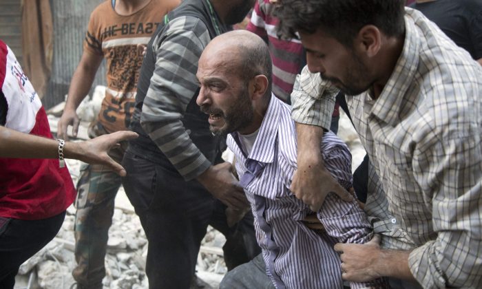 A grief-striken Syrian man is comforted by people as rescuers pull the body of his daughter from the rubble of a budling following government forces air strikes  in Aleppo on Sept. 27, 2016. (KARAM AL-MASRI/AFP/Getty Images)
