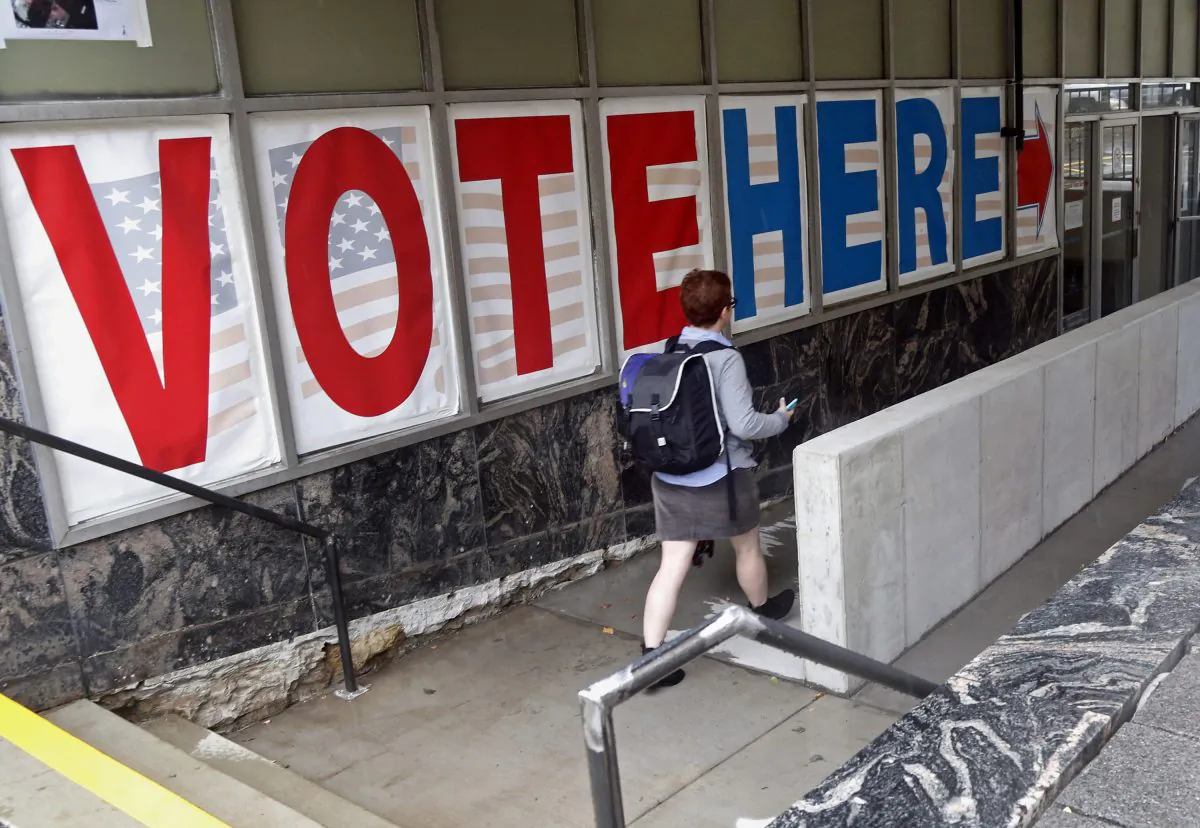 A voter woman passes a large sign before voting in Minneapolis on Sept. 23, 2016. (AP Photo/Jim Mone)
