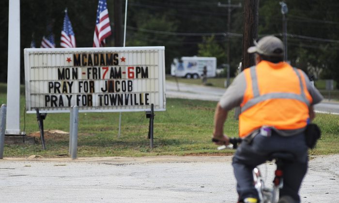 A bicyclist rides past a sign urging prayer for victims of a school shooting in Townville, S.C., on Sept. 29, 2016. (AP Photo/Jay Reeves)