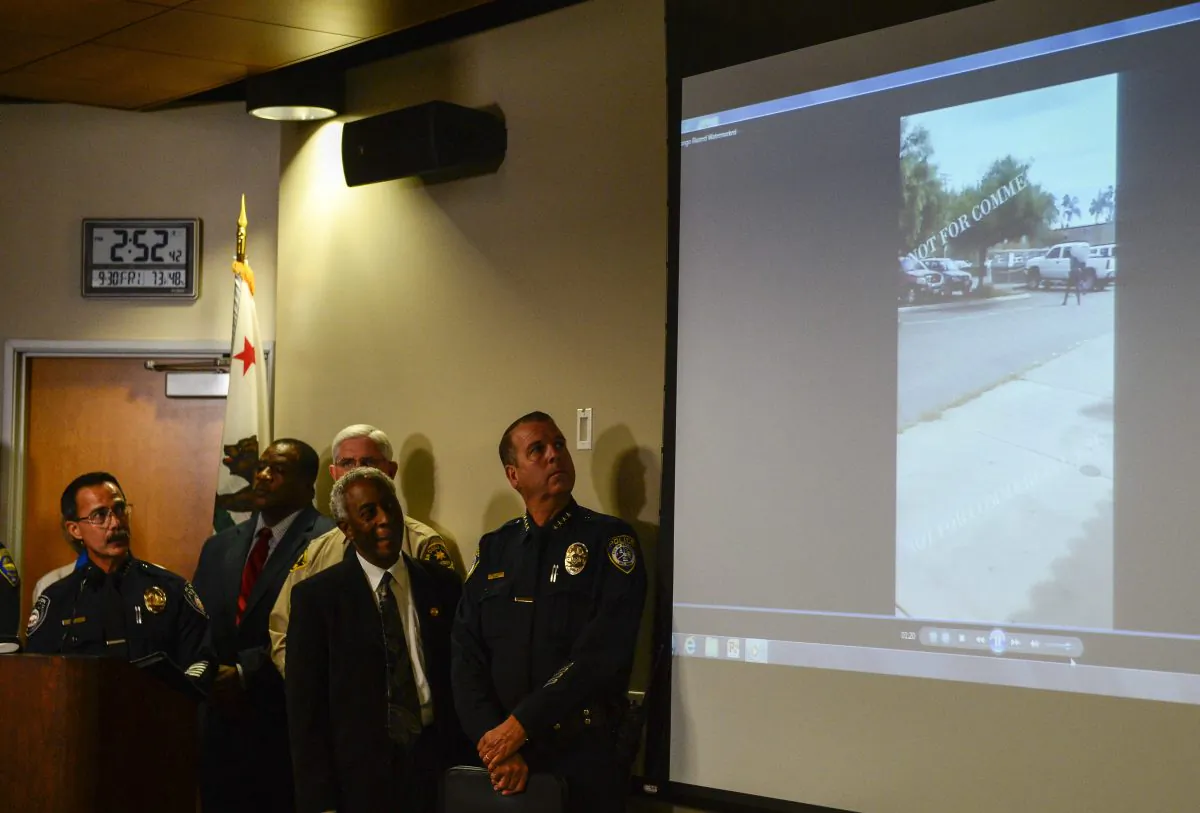 Authorities watch a video of the shooting scene at a news conference in El Cajon, Calif., on Sept. 30, 2016, held to address the killing of Alfred Olango, a Ugandan refugee shot by an El Cajon police officer on Tuesday. The El Cajon police department released video footage of the shooting at the news conference. (AP Photo/Denis Poroy)