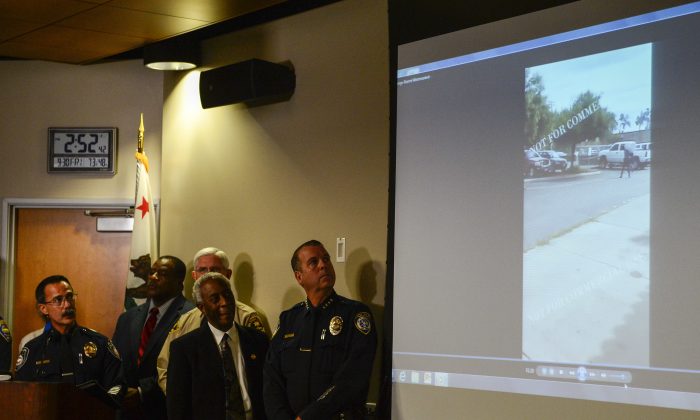 Authorities watch a video of the shooting scene at a news conference in El Cajon, Calif., on Sept. 30, 2016, held to address the killing of Alfred Olango, a Ugandan refugee shot by an El Cajon police officer on Tuesday. The El Cajon police department released video footage of the shooting at the news conference. (AP Photo/Denis Poroy)