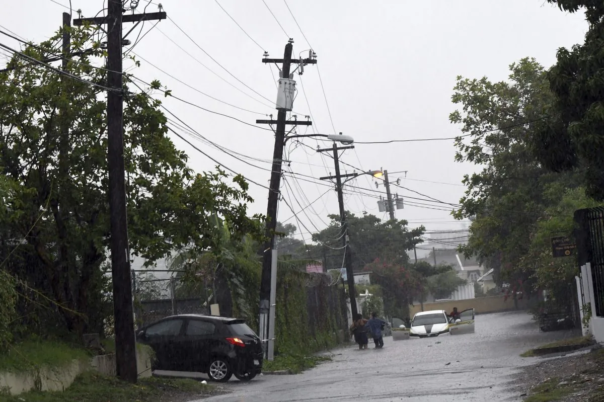 A car tries to cross a flooded street in downtown Kingston Jamaica, Sunday Oct. 2 , 2016.  (AP Photo/Collin Reid)