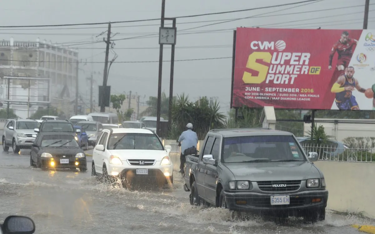 Cars drive along a street under heavy rain in downtown Kingston Jamaica, Sunday Oct. 2 , 2016. An extremely dangerous Hurricane Matthew is moving slowly over the Caribbean. It's following a track that authorities are warning could trigger devastation in parts of Haiti.(AP Photo/Collin Reid)
