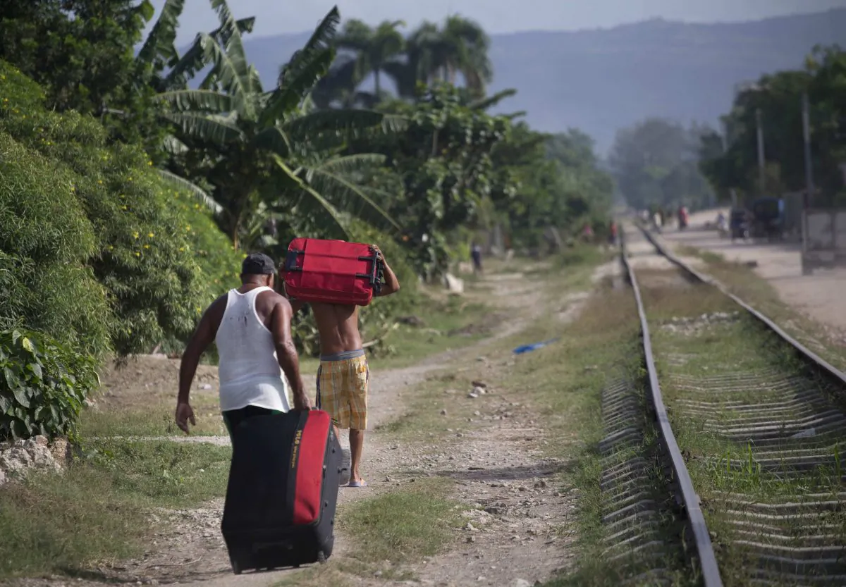 People carry suitcases as they move to a safer area before the arrival of Hurricane Matthew, in the village Paraguay, Guantanamo, Cuba, Monday, Oct. 3, 2016. A hurricane warning is in effect for Jamaica, Haiti, and the Cuban provinces of Guantanamo, Santiago de Cuba, Holguin, Granma and Las Tunas - as well as the southeastern Bahamas. (AP Photo/Ramon Espinosa)