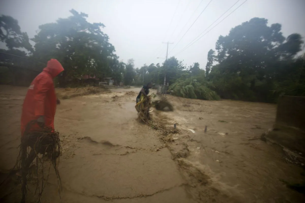 People work to remove debris from a street allowing vehicles to pass, in Leogane, Haiti, Tuesday, Oct. 4, 2016. Matthew slammed into Haiti's southwestern tip with howling, 145 mph winds Tuesday, tearing off roofs in the poor and largely rural area, uprooting trees and leaving rivers bloated and choked with debris.  ( AP Photo/Dieu Nalio Chery)