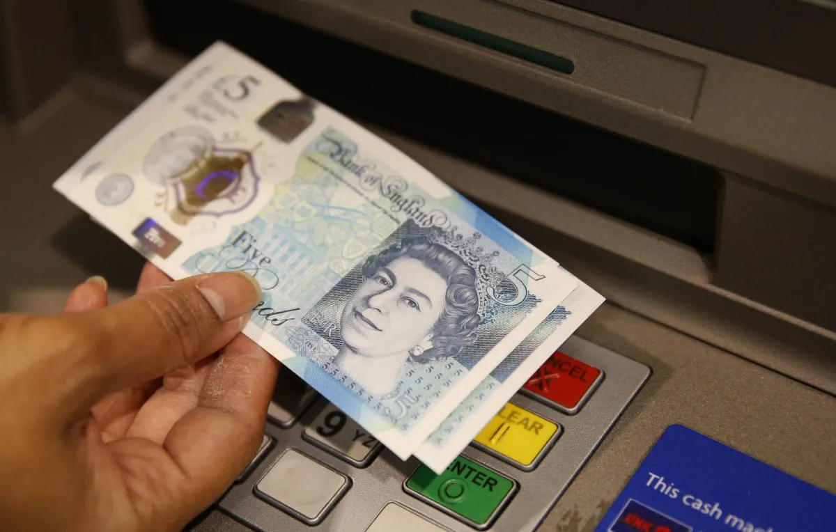 A member of staff at a branch of Halifax bank displays a new British £5 note, in London on Sept. 13, 2016. (Alastair Grant, File/AP Photo)