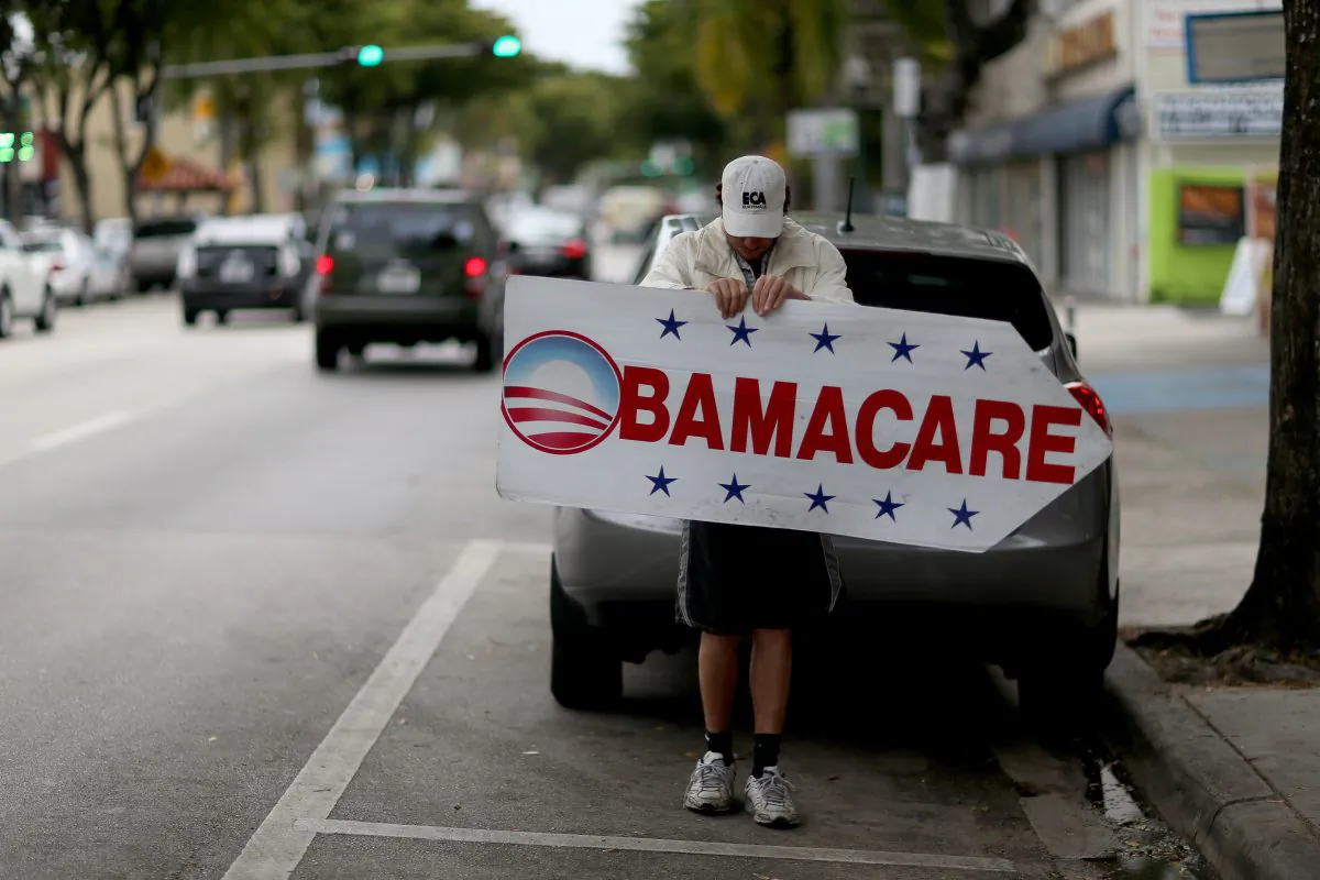 A man holds a sign directing people to an insurance company where they can sign up for the Affordable Care Act in Miami, Florida, on Feb. 5, 2015. (Joe Raedle/Getty Images)