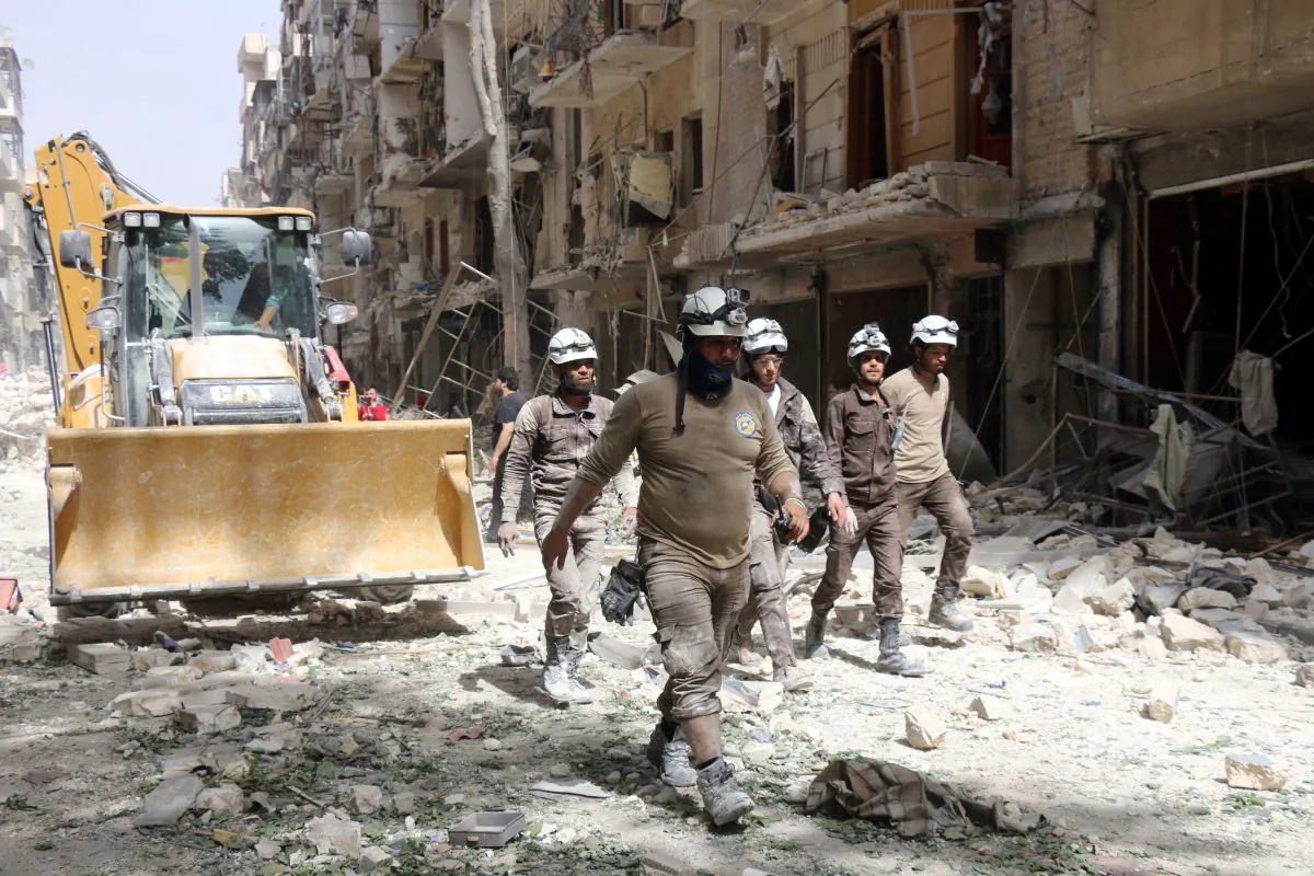 Syrian Civil Defense volunteers, known as the White Helmets, walk amidst the debris following a reported airstrike by Syrian government forces in the rebel-held neighborhood of Sukkari in the northern city of Aleppo on June 3, 2016. (Thaer Mohammed/AFP/Getty Images)