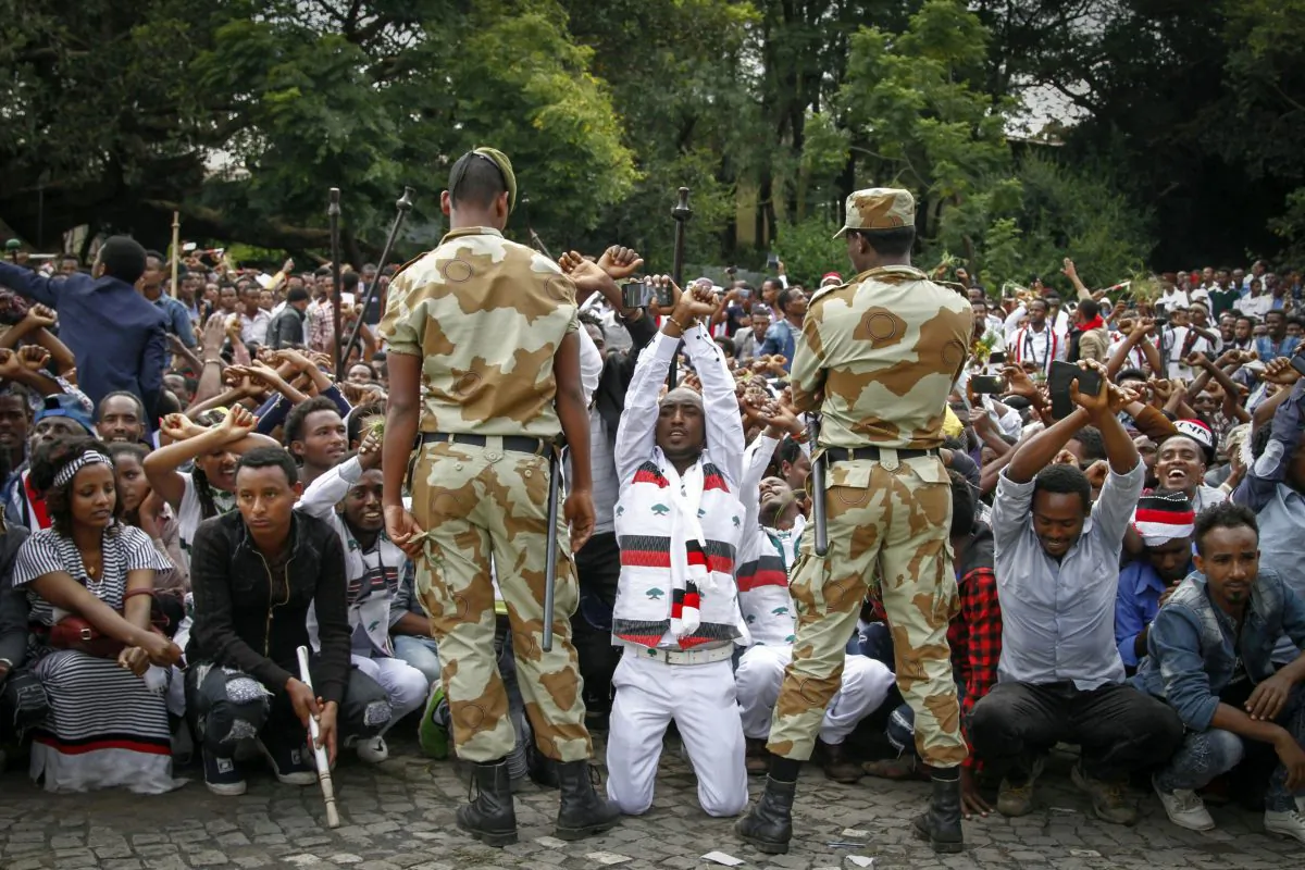 FILE - In this Sunday, Oct. 2, 2016 file photo, Ethiopian soldiers try to stop protesters in Bishoftu, in the Oromia region of Ethiopia. German Chancellor Angela Merkel is visiting Ethiopia on Tuesday, Oct. 11, 2016, where her meeting with Prime Minister Hailemariam Desalegn is expected to focus on the country's newly declared state of emergency after months of protests demanding wider freedoms, and other issues including migration. (AP Photo, File)