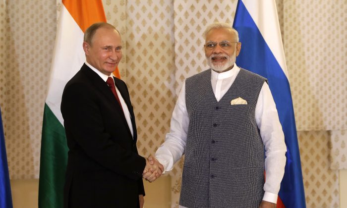 A file image of Indian Prime Minister Narendra Modi (right) shaking hands with Russian President Vladimir Putin prior to their annual bilateral meeting, on the sidelines of the BRICS summit in Goa, India, on Oct. 15, 2016. (AP Photo/Manish Swarup)