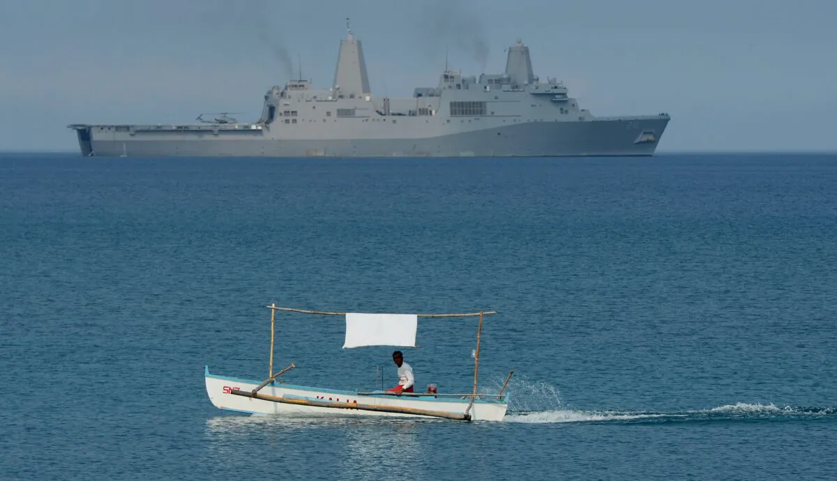 A Filipino fisherman motors past the U.S. Navy amphibious transport dock ship USS Green Bay (LPD-20) during joint exercises on a beach at San Antonio off Zambales province in the Philippines in April 2015. (Ted Aljibe/AFP/Getty Images)