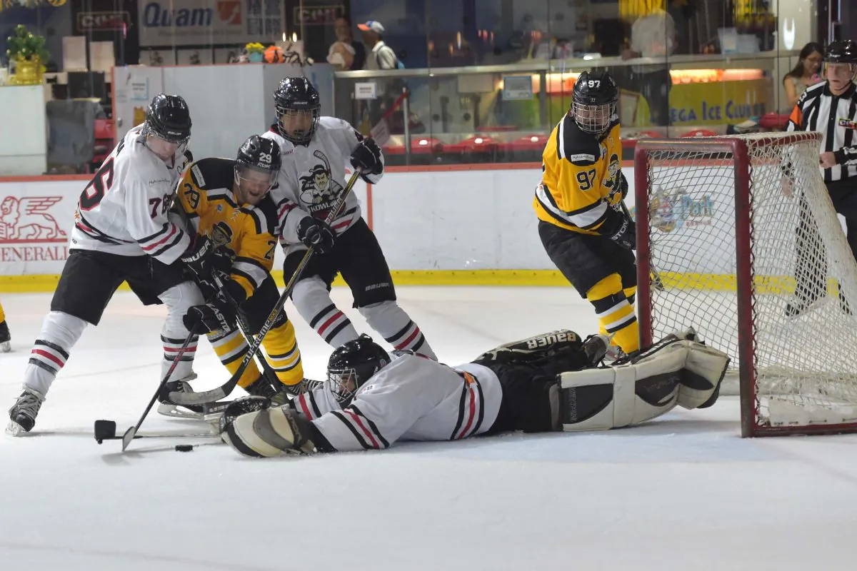 Warrior’s goalie Loron Oris reaches for the puck as Tycoons attacker Joel Anharberg gets sandwiched out by Darren Winnia (76) and Jonathan Yiu, as Don Ho (97) watches with anguish. in their CIHL match at Mega Ice on Thursday Oct 20, 2016. (Bill Cox/Epoch Times)