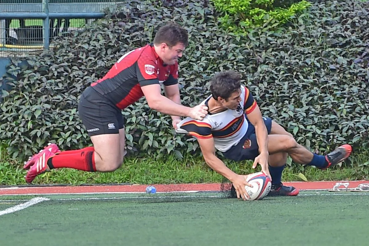 Hong Kong Cricket Club’s Rowan Varty just keeps his foot in play to score, under pressure from Mathew Bell of Valley to push HKCC into a 5-0 lead in their HKR Premiership match at Happy Valley on Saturday Oct 22. Cricket Club went on to win the match 15-10 to hand Valley their first defeat of the season. (Bill Cox/Epoch Times)