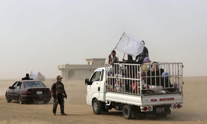 A member of Iraq's elite counterterrorism forces watches a truck carrying fleeing civilians drive off, as Iraq's elite counterterrorism forces fight against Islamic State militants, in the village of Tob Zawa, about 9 kilometers (5.6 miles) from Mosul, Iraq, Tuesday, Oct. 25, 2016. (AP Photo/Khalid Mohammed)