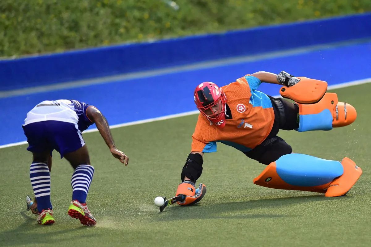 KNS Goalie Chan Hou Fung dives to stop a shot from an SSSC attacker , while his teammate backs up, during their premier division match at King’s Park on Sunday Oct 23. (Bill Cox/Epoch Times)