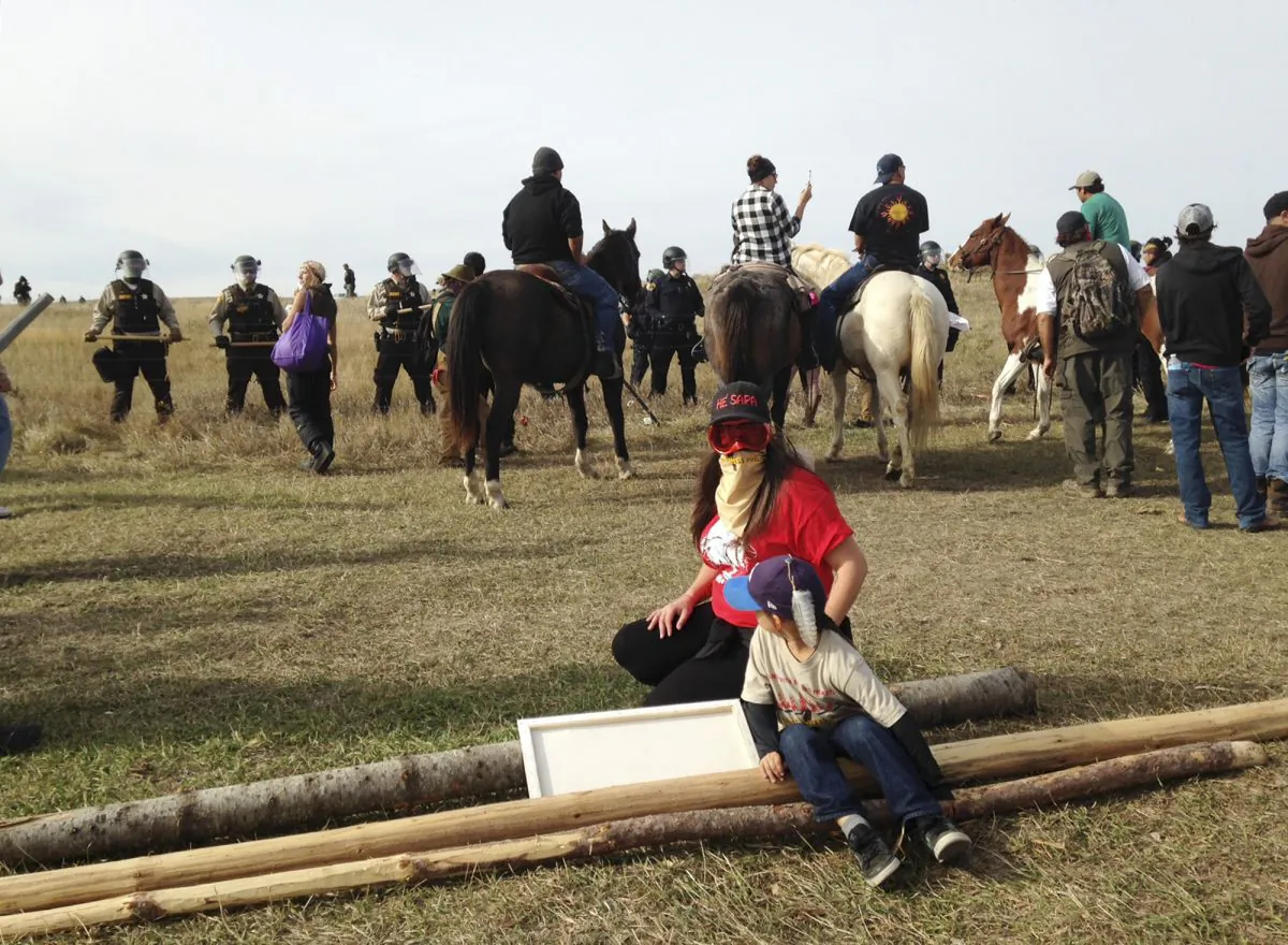 Dakota Access pipeline protesters stand in defiance of law enforcement officers who are trying to force them from a camp on private land in the path of pipeline construction  near Cannon Ball, N.D., on Oct. 27, 2016. (James MacPherson/AP Photo)