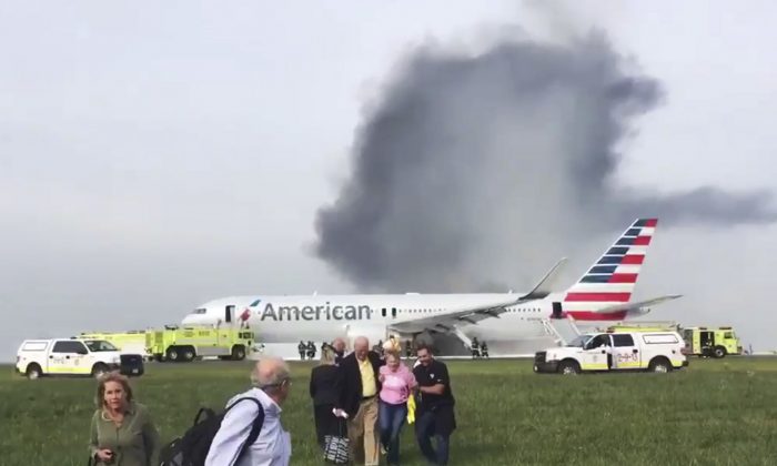 In this photo provided by passenger Jose Castillo, fellow passengers walk away from a burning American Airlines jet that aborted takeoff and caught fire on the runway at Chicago's O'Hare International Airport on Friday, Oct. 28, 2016. Pilots on Flight 383 bound for Miami reported an engine-related mechanical issue, according to an airline spokeswoman. (Jose Castillo via AP)