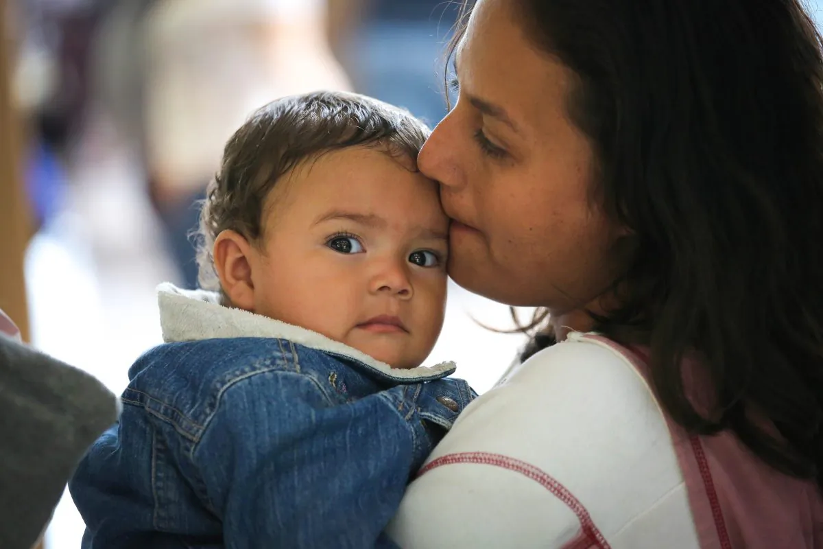 An illegal immigrant mother and child from Honduras wait to take a bus to Florida from McAllen, Texas, on Aug. 19. After crossing the border, families are given temporary legal documents by U.S. Border Patrol, then sent to their destination city, where they apply for political asylum. (John Moore/Getty Images)