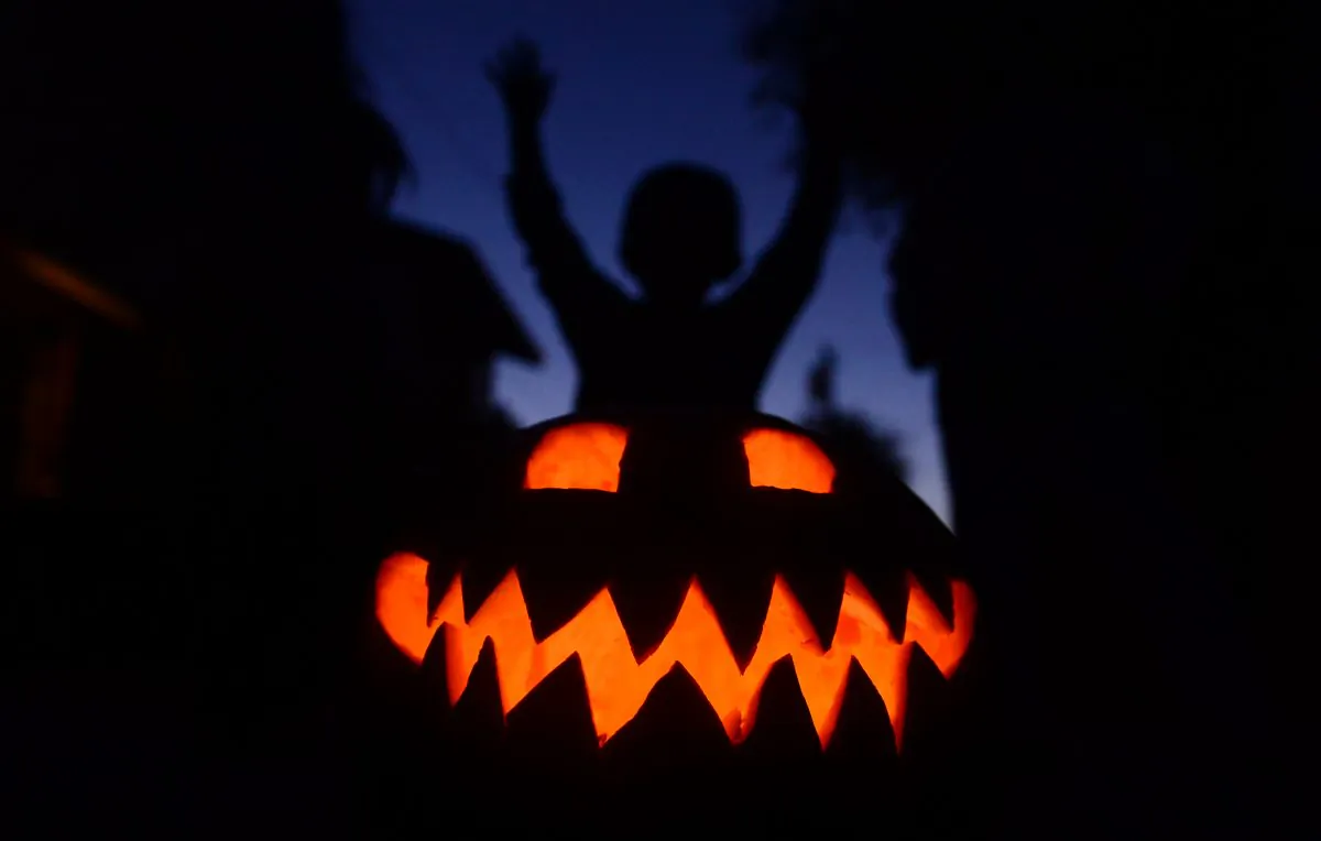 Children play behind a pumpkin carved and lit for Halloween in a file photo. (Frederic J. Brown/AFP/Getty Images)