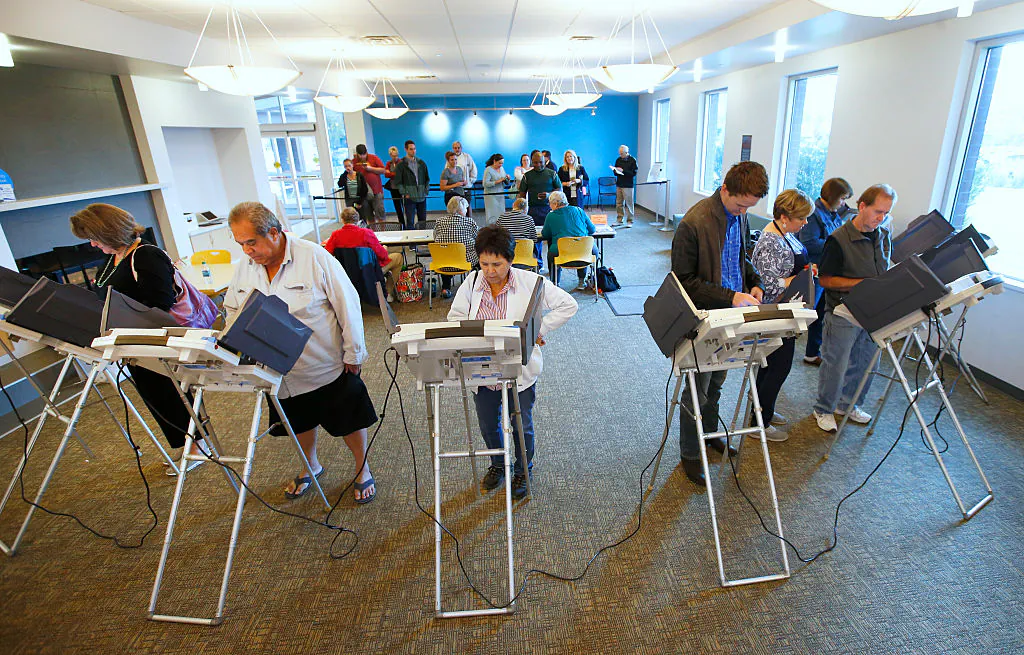 People wait in line and cast their ballots on electronic voting machines on Oct. 25, in Provo, Utah. The GEMS system that counts votes in a quarter of the United States contains code to alter how votes are weighted. (George Frey/Getty Images)
