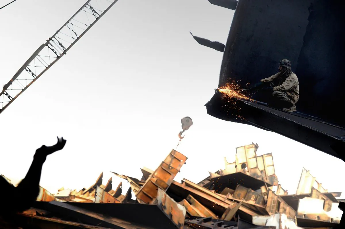 In this photograph taken on July 9, 2012, a Pakistani shipyard worker uses a blow torch to cut through a metal platform of a vessel beached and being dismantled at one of the 127 ship-breaking plots in Geddani, some 40Kms west of Karachi.  Geddani's ship-breaking yards employ some 10,000 workers including welders, cleaners, crane operators and worker supervisors. The yards are one of the largest ship-breaking operations in the world rivaling in size those located in India and Bangladesh. It takes 50 workers about three months to break down a midsize average transport sea vessel of about 40,000 tonnes. The multimillion-dollar ship-breaking industry contributes significantly to the national supply of steel to Pakistani industries. For a six-day working week of hard and often dangerous work handling asbestos, heavy metals and polychlorinated biphenyls (PCBs), employees get paid about 300 USD a month of which half is spent on food and rent for run-down rickety shacks near the yards, a labour representative told AFP.     AFP PHOTO / Roberto SCHMIDT        (Photo credit should read ROBERTO SCHMIDT/AFP/GettyImages)