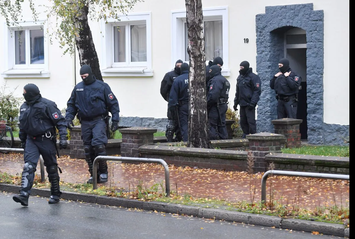 Police officers seach a residential building opposite the German-Speaking Islamic Circle Hildesheim mosque in Hildesheim, Germany, Tuesday, Nov. 8, 2016. German security authorities arrested five men Tuesday on allegations they aided the Islamic State group in Germany, recruiting members and providing financial and logistical help. (Julian Stratenschulte/dpa via AP)