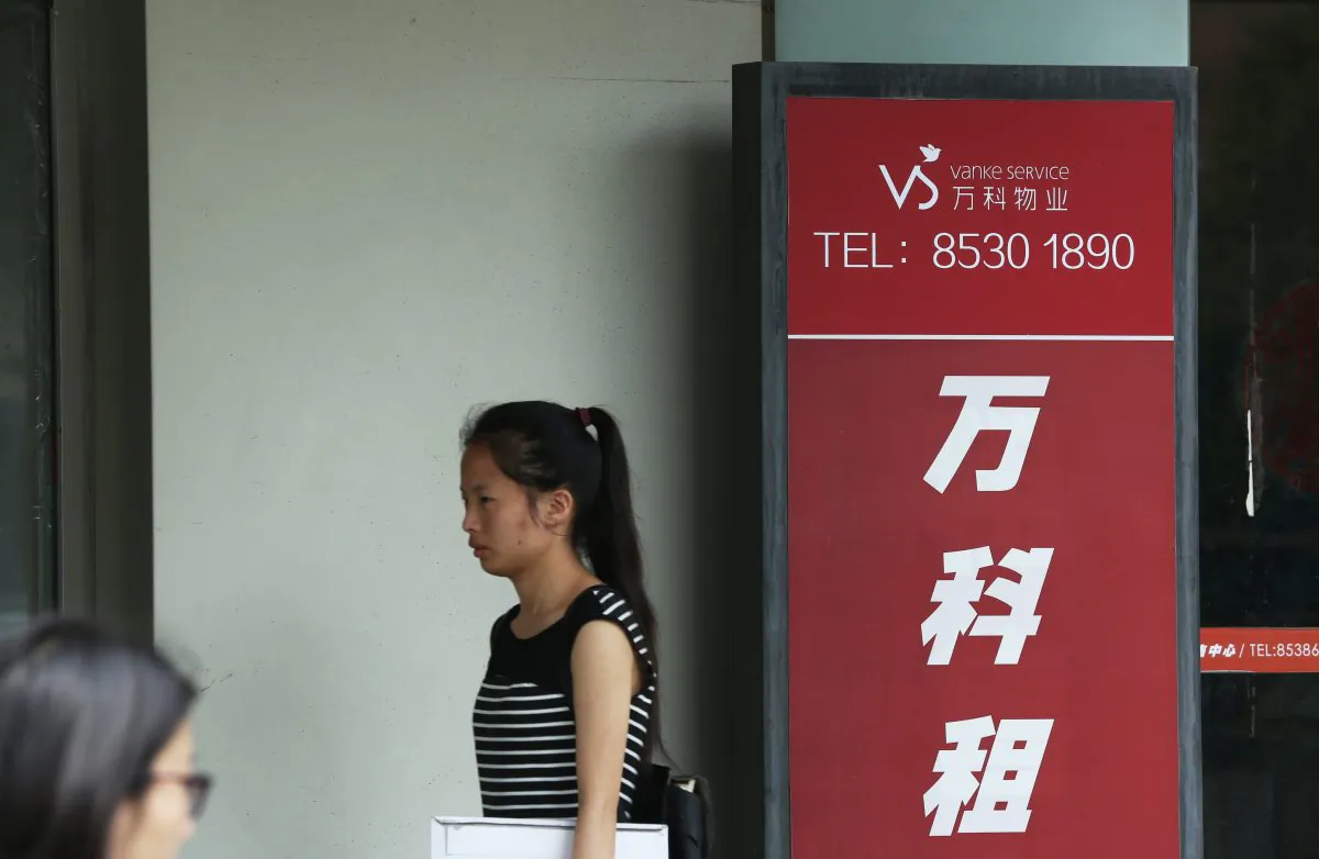 A woman walks past a Vanke Service Center in Beijing July 6, 2016.
(STR/AFP/Getty Images)