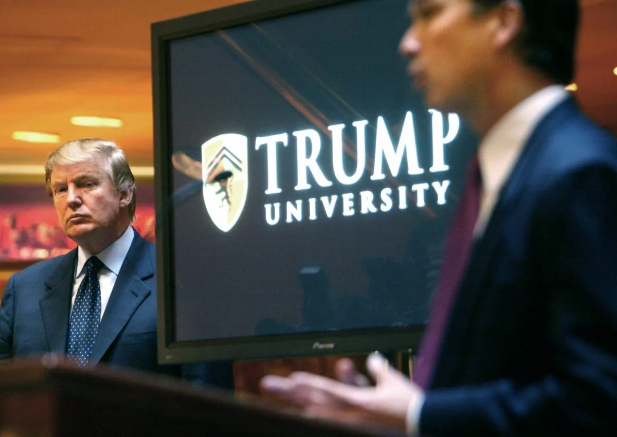 Then real estate mogul and Reality TV star Donald Trump (L) listens as Michael Sexton introduces him at a news conference in New York where he announced the establishment of Trump University, on May 23, 2005. (AP Photo/Bebeto Matthews)