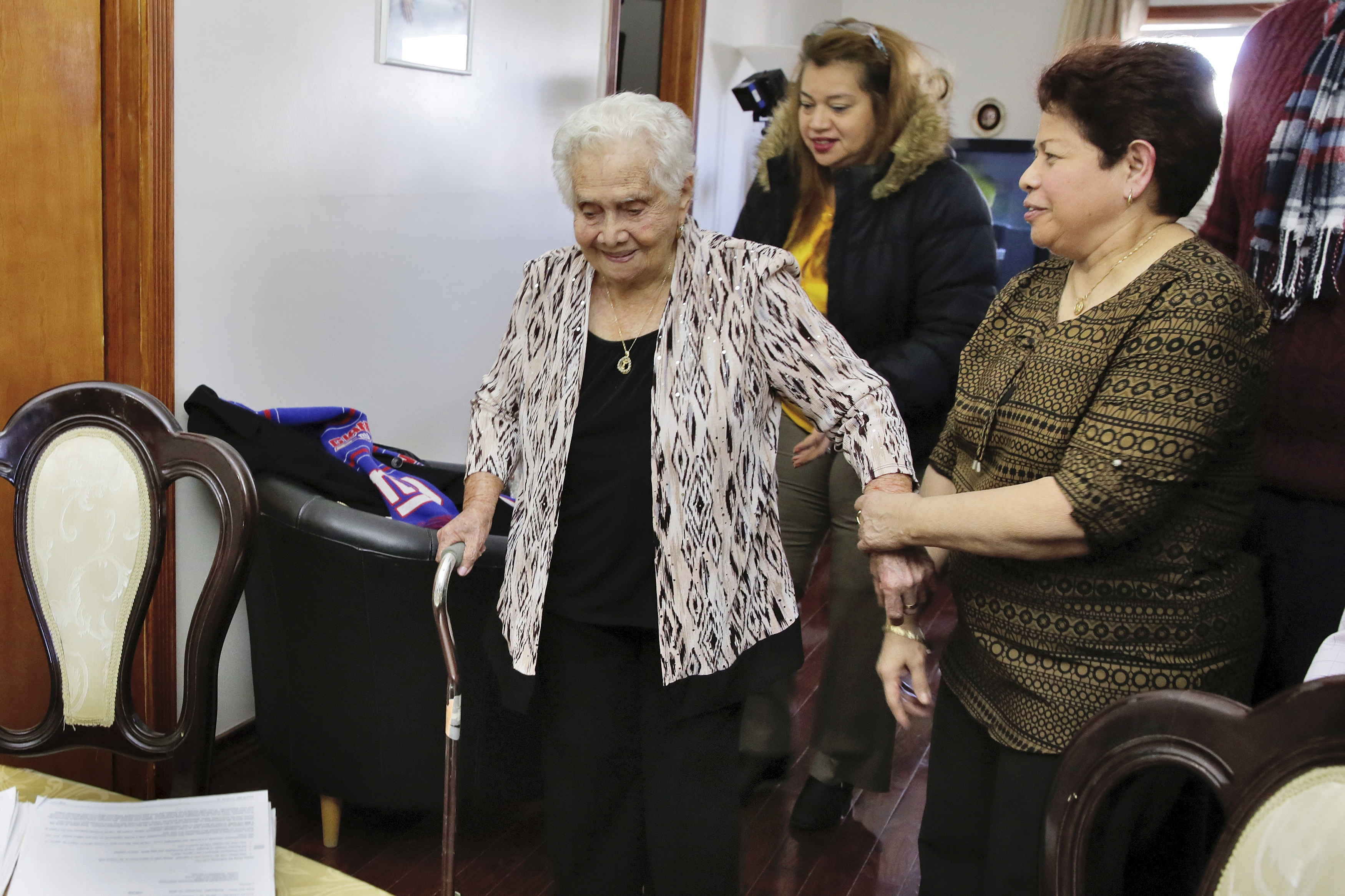 America Maria Hernandez, 99 (L) is aided by her granddaughter Monica Martinez (C) and daughter Ana Martinez as she prepares to take the Naturalization Oath of Allegiance, in the Queens borough of New York on Nov. 23, 2016. (AP Photo/Richard Drew)