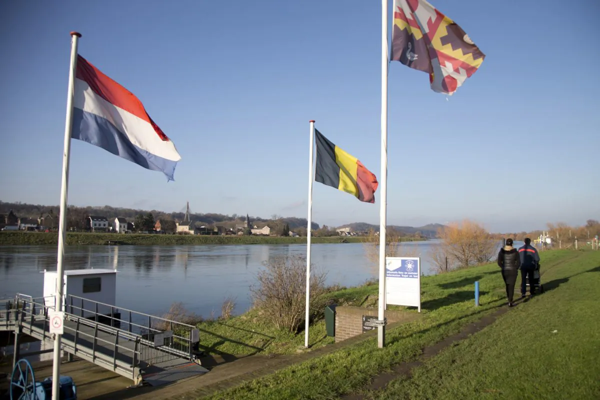 People walk past Dutch and Belgian flags on the waterfront in Eijsden, Netherlands. The Netherlands and Belgium on Nov. 28, 2016 signed a deal for a peaceful exchange of land between them for the mere fact that it makes sense to do so. (AP Photo/Virginia Mayo, File)