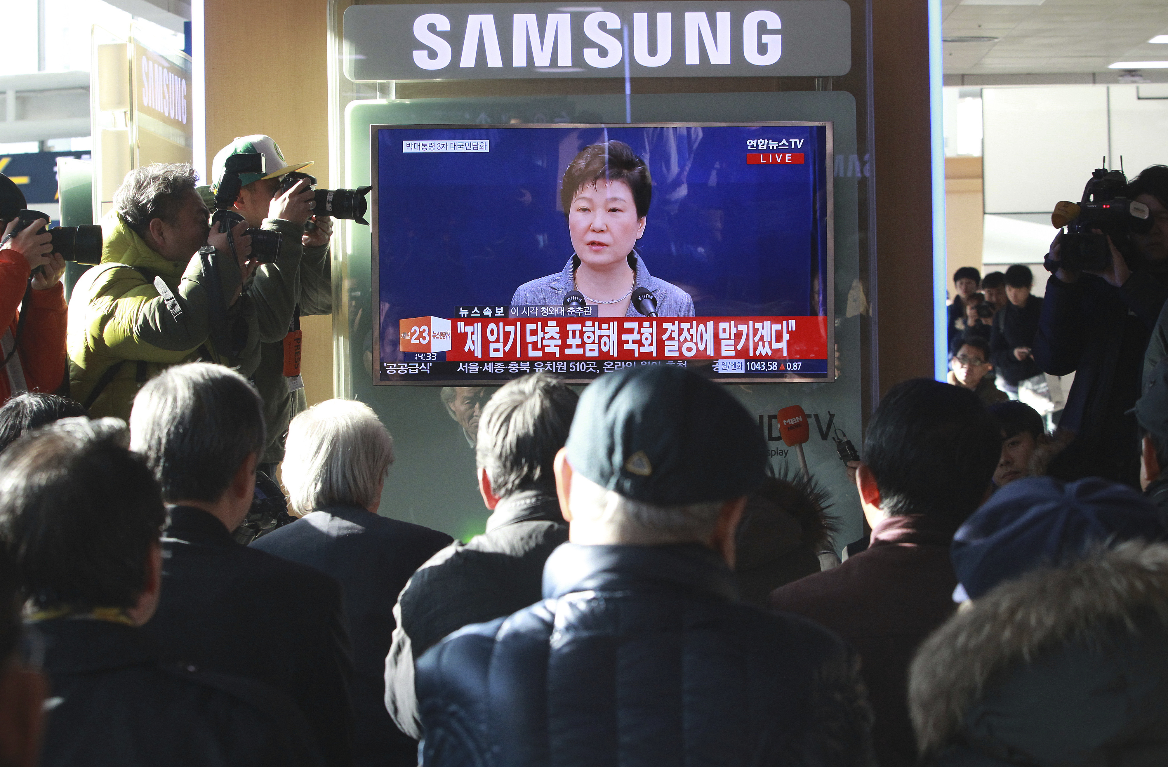 People watch a TV screen showing the live broadcast of South Korean President Park Geun-hye's addressing to the nation, at the Seoul Railway Station in Seoul, South Korea on Nov. 29, 2016. (AP Photo/Ahn Young-joon)