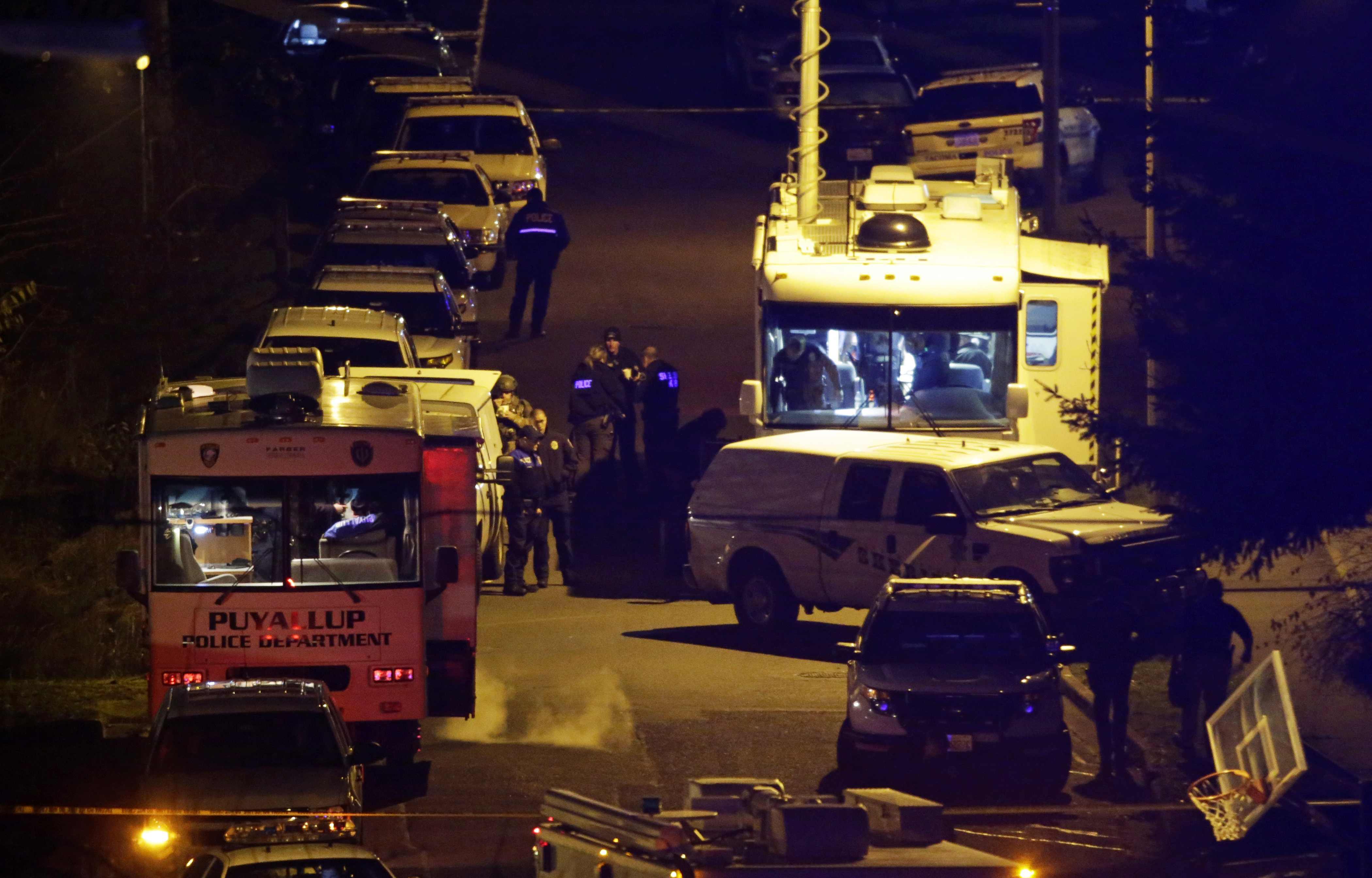 Law enforcement officers stand by command vehicles on East 52nd Street in Tacoma, Wash., on Dec. 1, 2016. (AP Photo/Ted S. Warren)