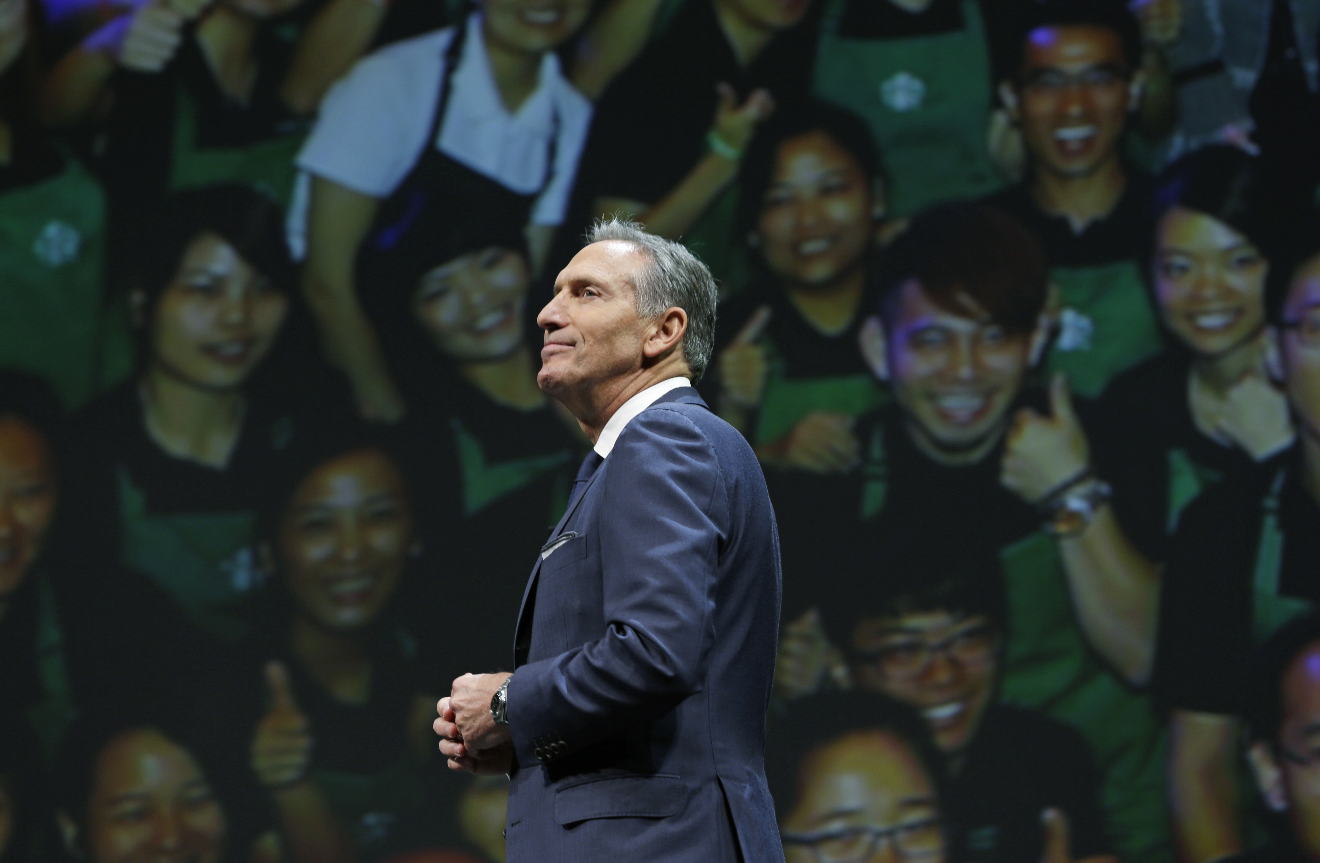 Starbucks CEO Howard Schultz walks in front of a photo of Starbucks baristas, at the coffee company's annual shareholders meeting in Seattle, in this file photo. (AP Photo/Ted S. Warren)