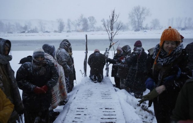 In this Tuesday, Nov. 29, 2016 photo, a person prays along the Cannonball River during a Native American water ceremony at the Oceti Sakowin camp where people have gathered to protest the Dakota Access oil pipeline in Cannon Ball, N.D. So far, those fighting the Dakota Access pipeline have shrugged off the heavy snow, icy winds and frigid temperatures that have swirled around their large encampment on the North Dakota grasslands. (AP Photo/David Goldman)