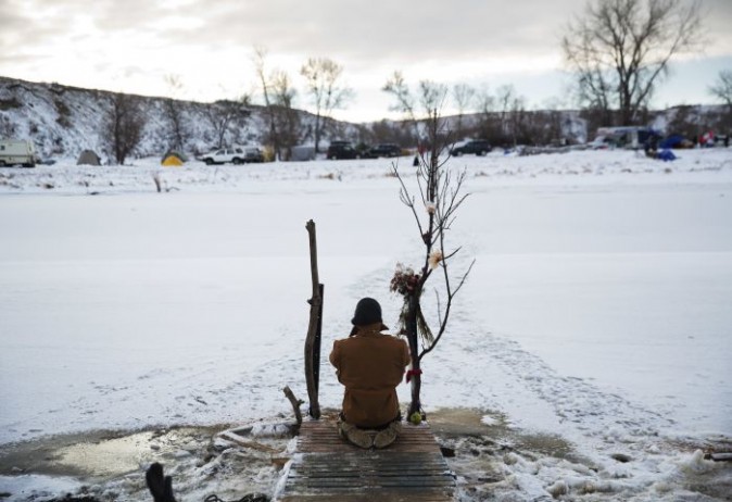 Army veteran Nick Biernacki, of Indiana, prays at the Cannonball River at the Oceti Sakowin camp where people have gathered to protest the Dakota Access oil pipeline in Cannon Ball, N.D., Sunday, Dec. 4, 2016. Tribal elders have asked the military veterans joining the large Dakota Access pipeline protest encampment not to have confrontations with law enforcement officials, an organizer with Veterans Stand for Standing Rock said Sunday, adding the group is there to help out those who've dug in against the four-state, $3.8 billion project. (AP Photo/David Goldman)