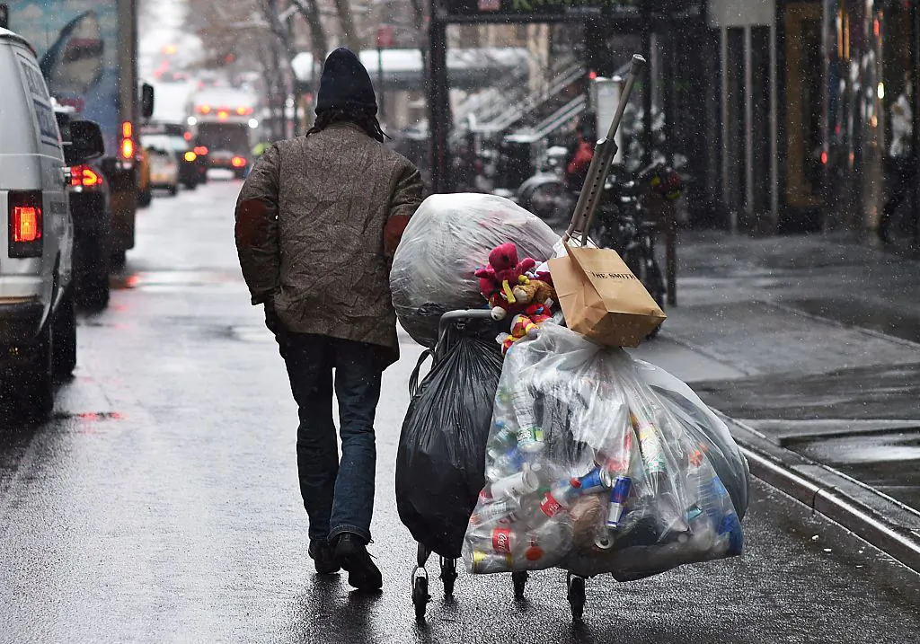 A man walks with a cart of recyclable bottles and cans along a street during a wet snowfall in New York on March 4, 2016 (JEWEL SAMAD/AFP/Getty Images)