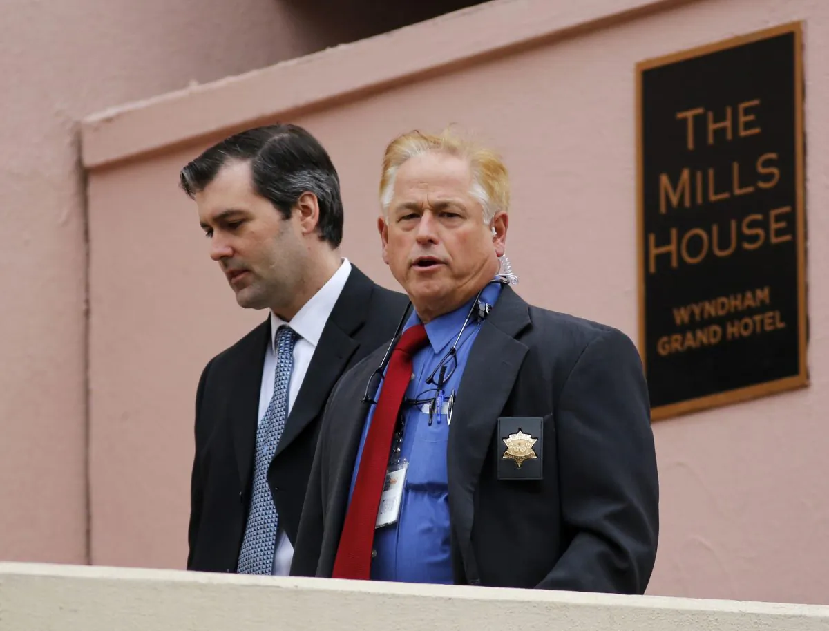 Michael Slager, left, walks from The Mills House Hotel to the Charleston County Courthouse under the protection from the Charleston County Sheriff's Department during a break in the jury deliberations for his trial Monday, Dec. 5, 2016, in Charleston, S.C. Former North Charleston police officer, Slager, is charged with murder in the shooting death last year of Walter Scott. (AP Photo/Mic Smith)